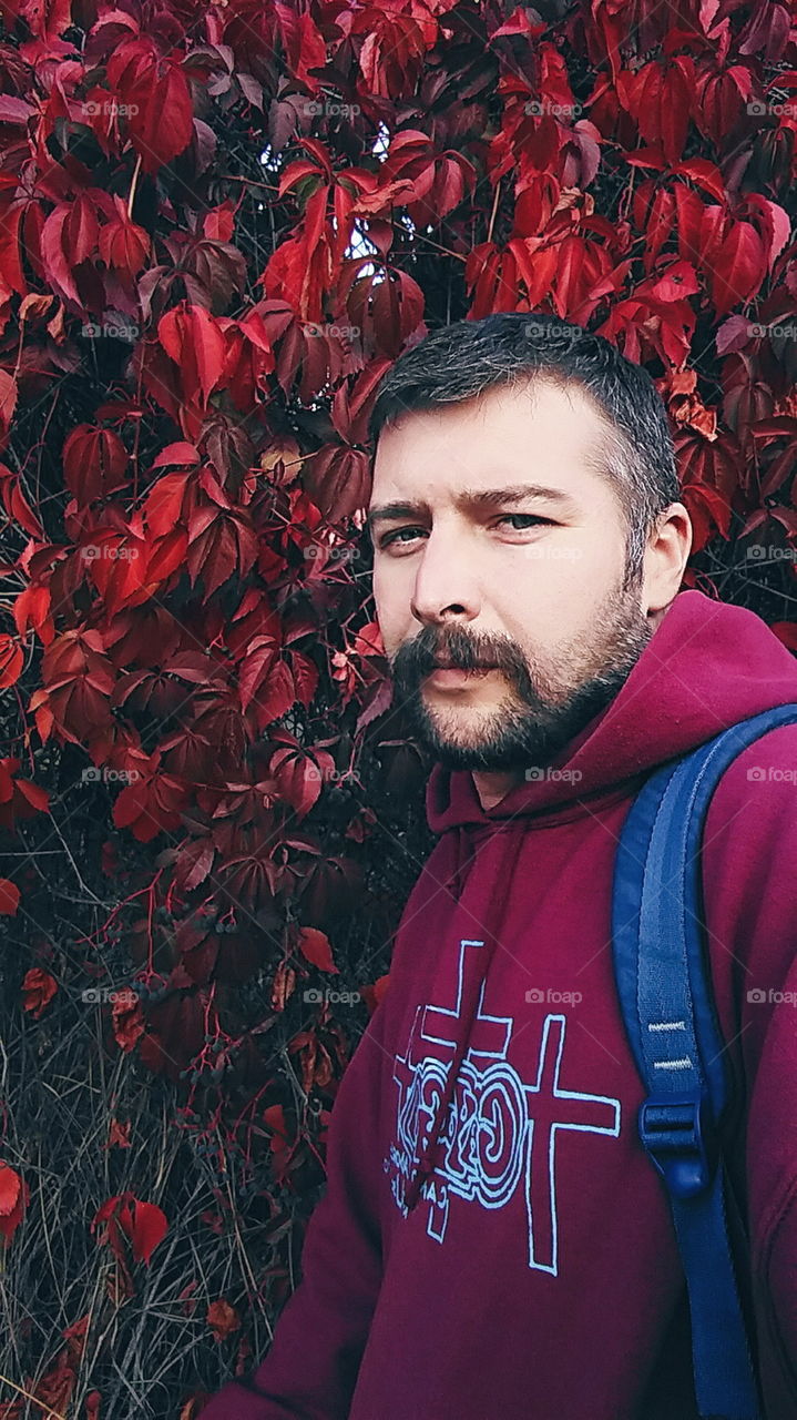 a man with a beard against the backdrop of autumn leaves