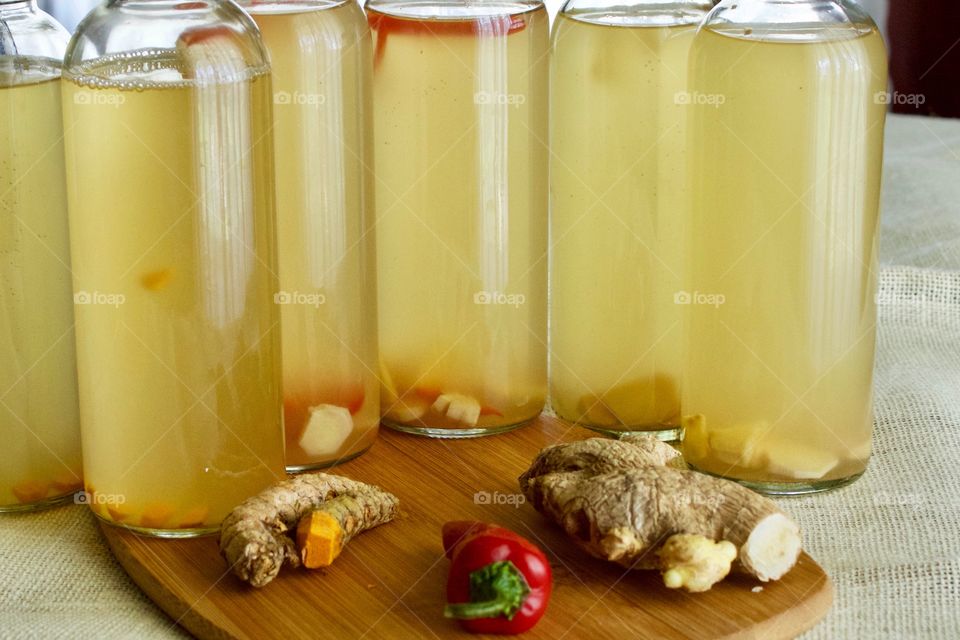 Ingredients to flavor homemade kombucha which is bottled for a second ferment — turmeric root, red chili pepper, and ginger root, on bamboo cutting board 