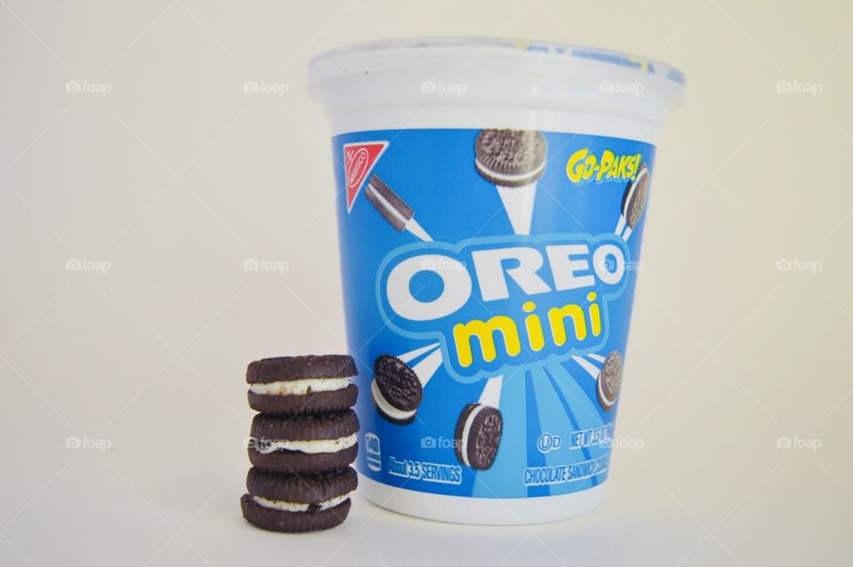 Oreo mini cookies stacked in front of container with white background 