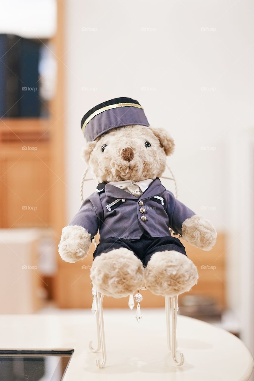 Cute teddy bear. A cute teddy bear wearing a bell boy uniform sitting on a chair in hotel lobby, with soft focus on the bear's nose.