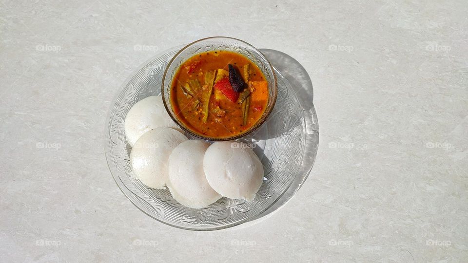 Idli and sambar, sambar a vegetable curry medium spicy, Idli is a pure white colour fluffy steamed batter consisting of fermented black lentils (de-husked) and rice