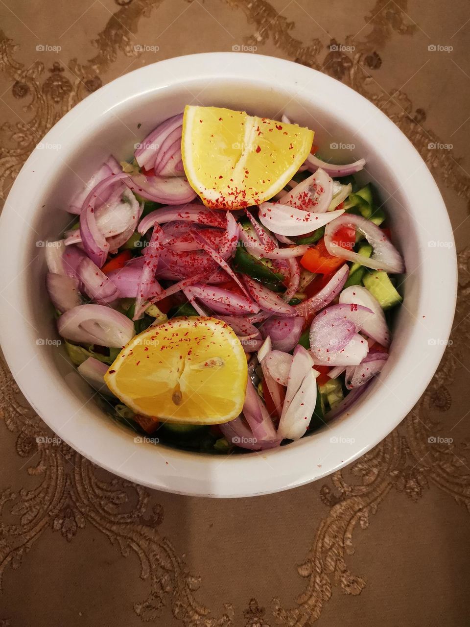 The salad is onions, cucumbers, tomatoes, green peppers, tomatoes, lemons