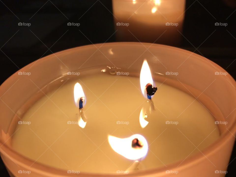 Brightly lit candle with three wicks