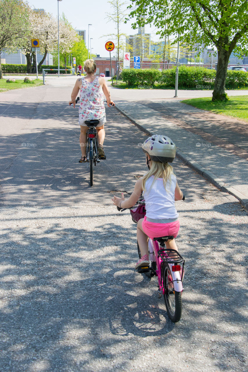 Young girl is riding her bike with her mother in the city of Malmö Sweden.
