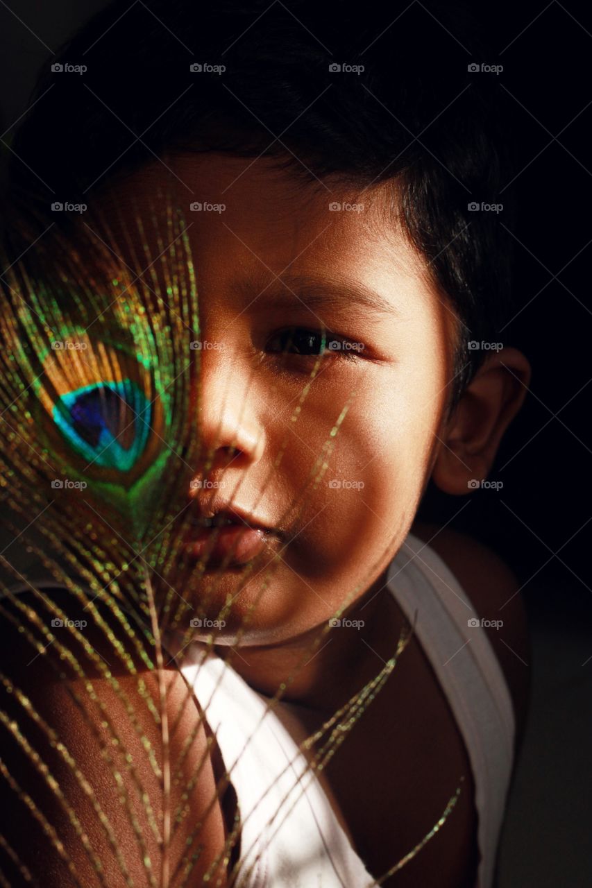 baby boy with peacock feather in natural filter