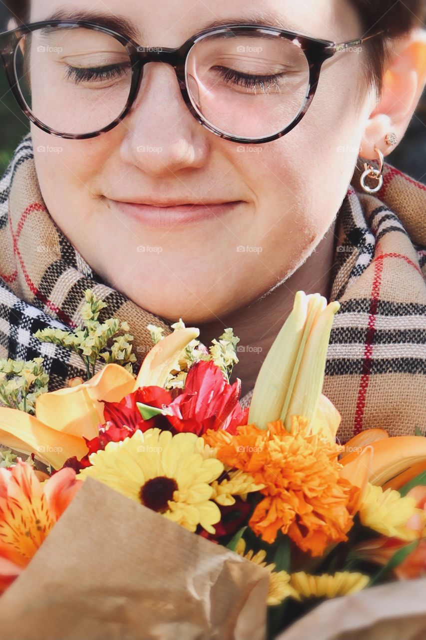 A young woman admires a fresh Autumnal bouquet of flowers while enjoying a sunny October afternoon 