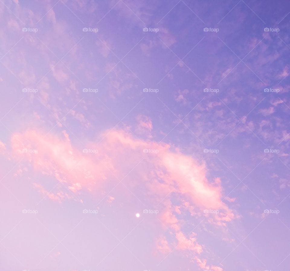 Cotton candy-colored, pink, purple sky with clouds and a white moon