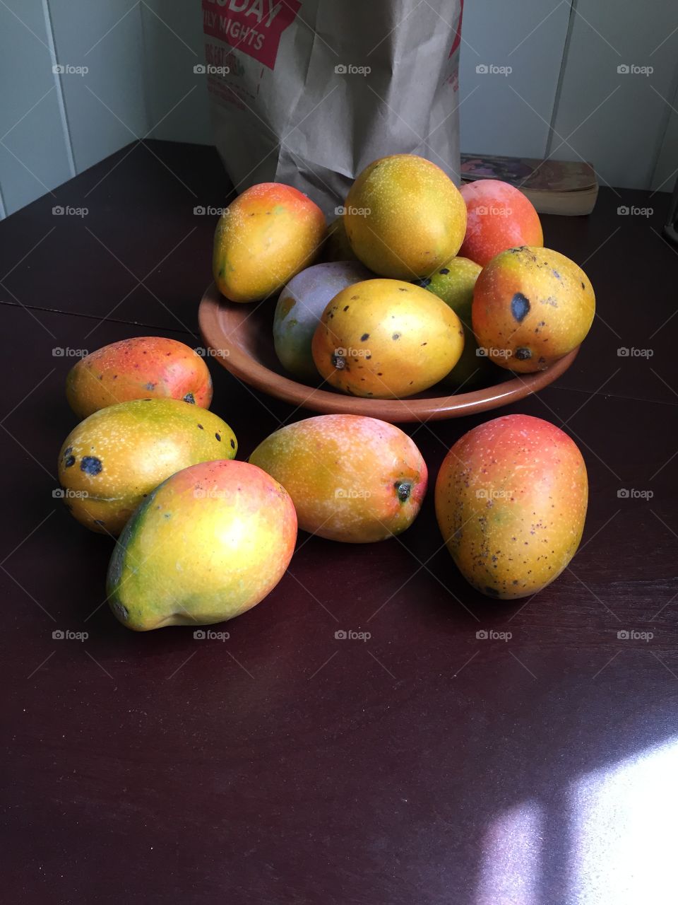 Ripe mangoes in a mahogany bowl. 
