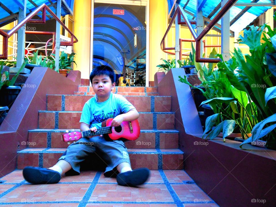 asian child with a yukelele or small guitar