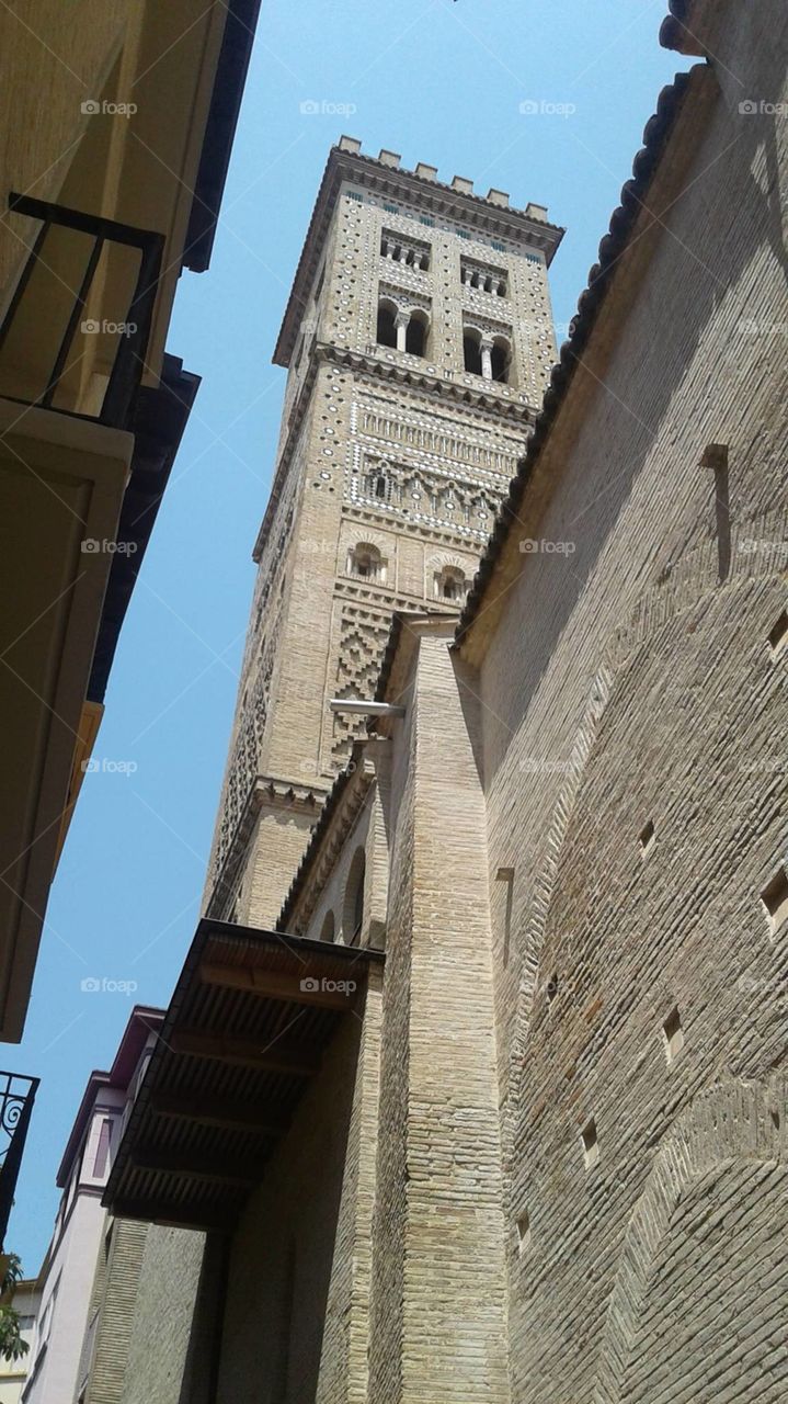 Narrow alley between the angular sandstone buildings of a Spanish city.