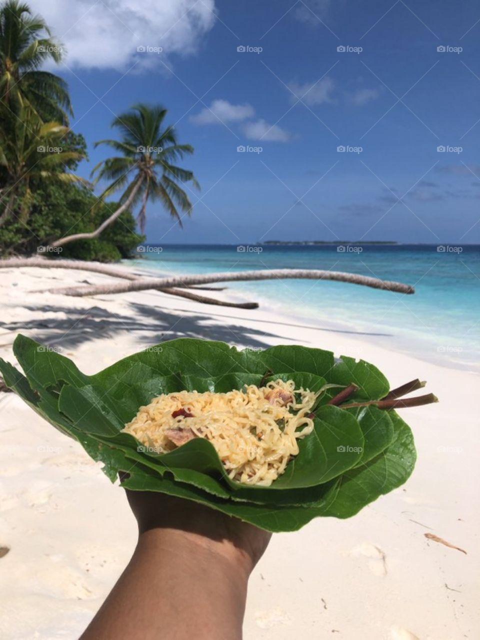 Tasty home made noodles on a leave used as plates during fun trips activities on a nice beach full of white sand, crystal clear lagoon.