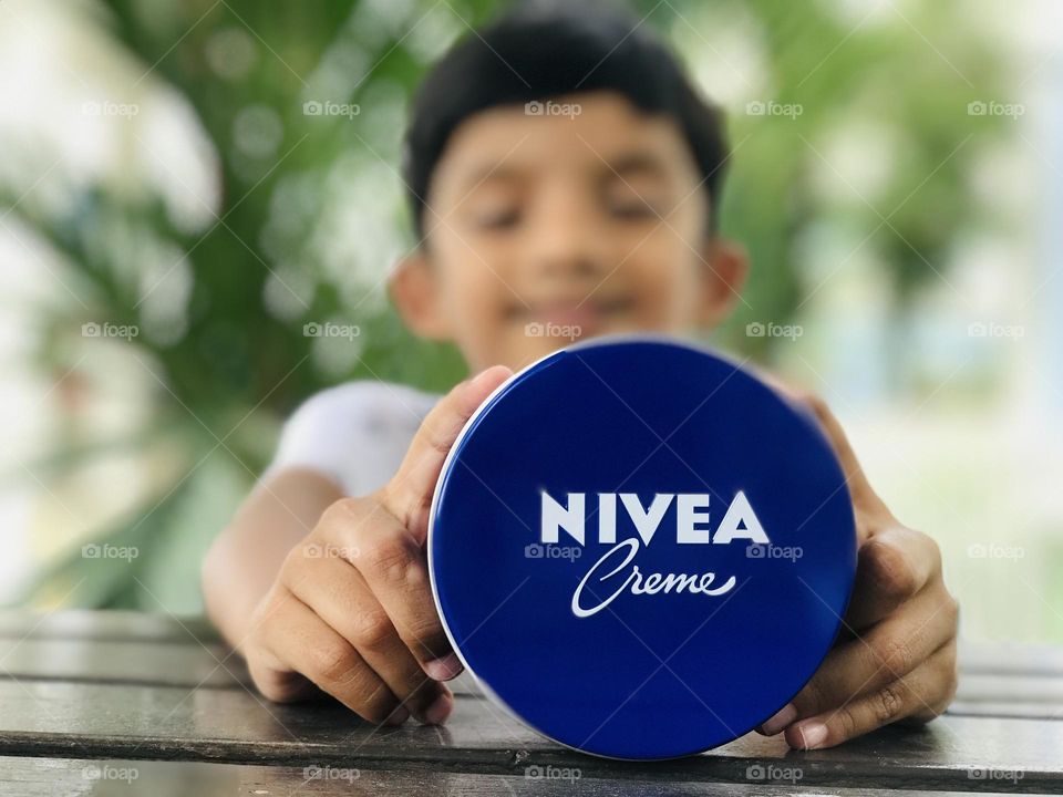 A boy holds Nivea cream.