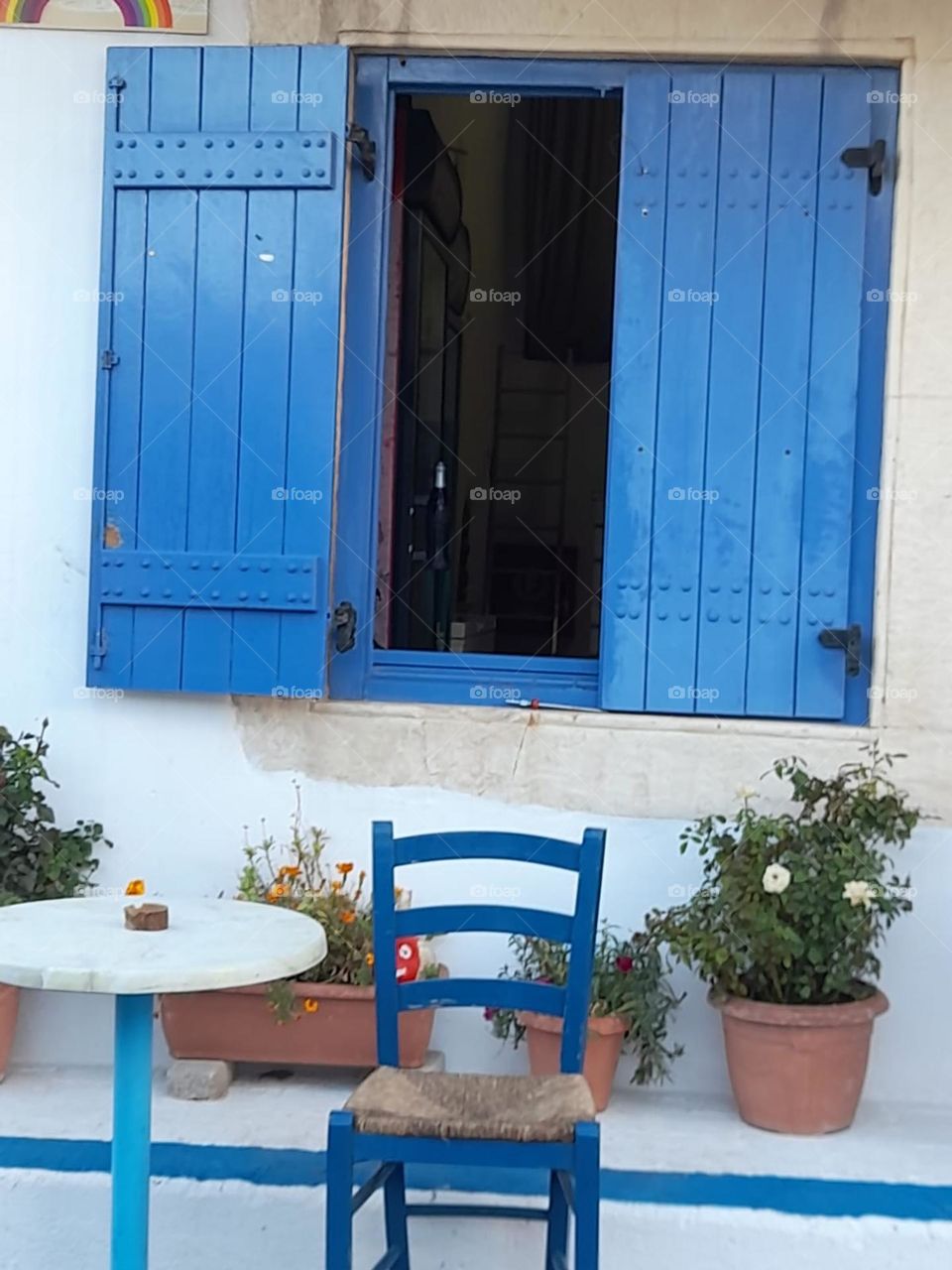 greece. blue shutters table and chair plants. greek. outdoor