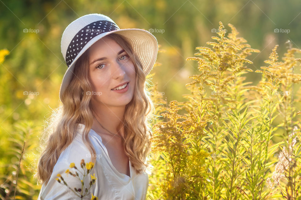 Emotional portrait of a happy and cheerful beautiful girl in a hat in the sunset light.