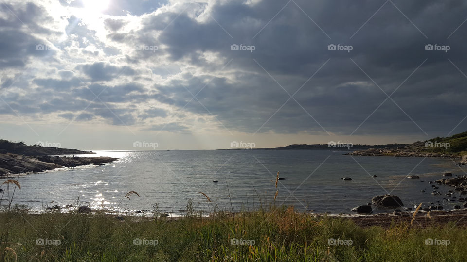 By the sea, sun shines through the clouds.
Vid havet, solen skiner genom molnen 