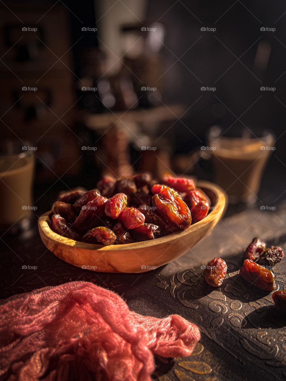 Dates dried fruits in a wooden bowl and some scattered on the table with vintage looks.