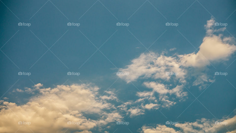 Large clouds float across the sunset sky like sails.