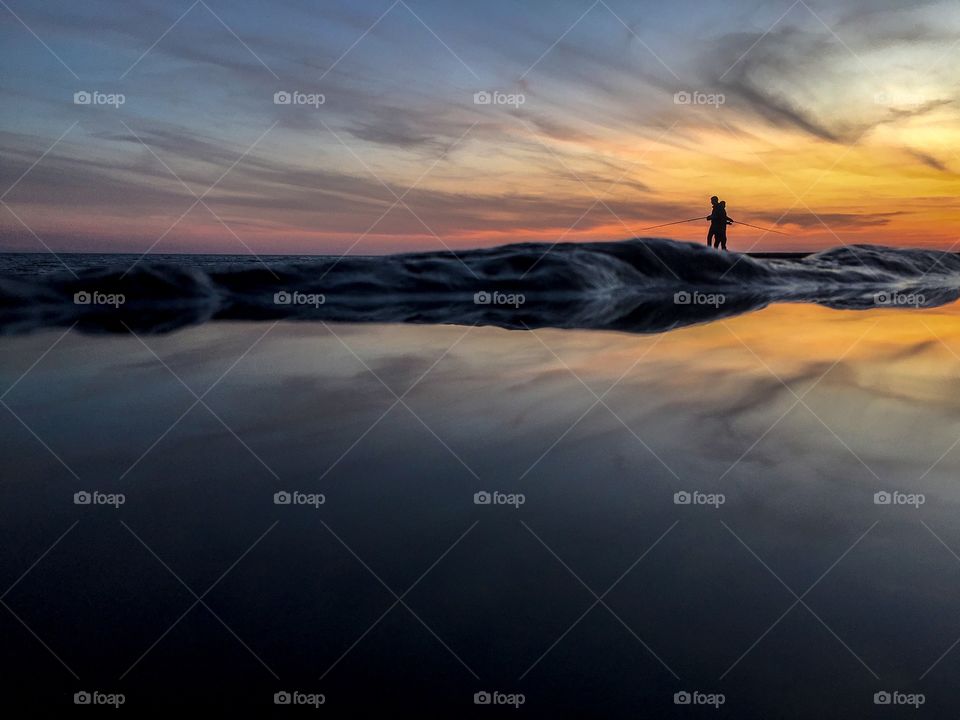 Fishermen enjoying fishing at sunset. Reflection of the sea. 