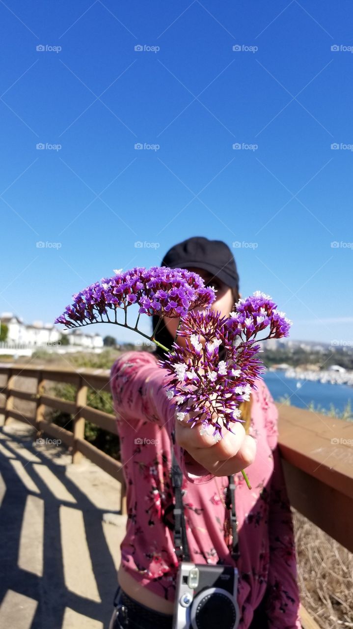 fashionable woman holding a sea lavender flower against the beautiful view of the bay and the city