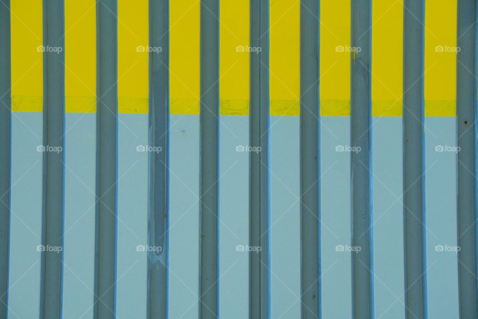A decorative yellow and gray metal industrial fence.