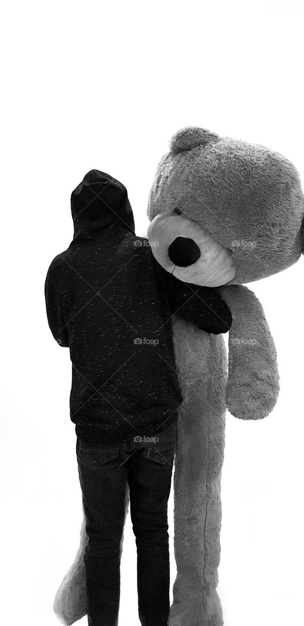 A guy hugging a large stuffed bear
