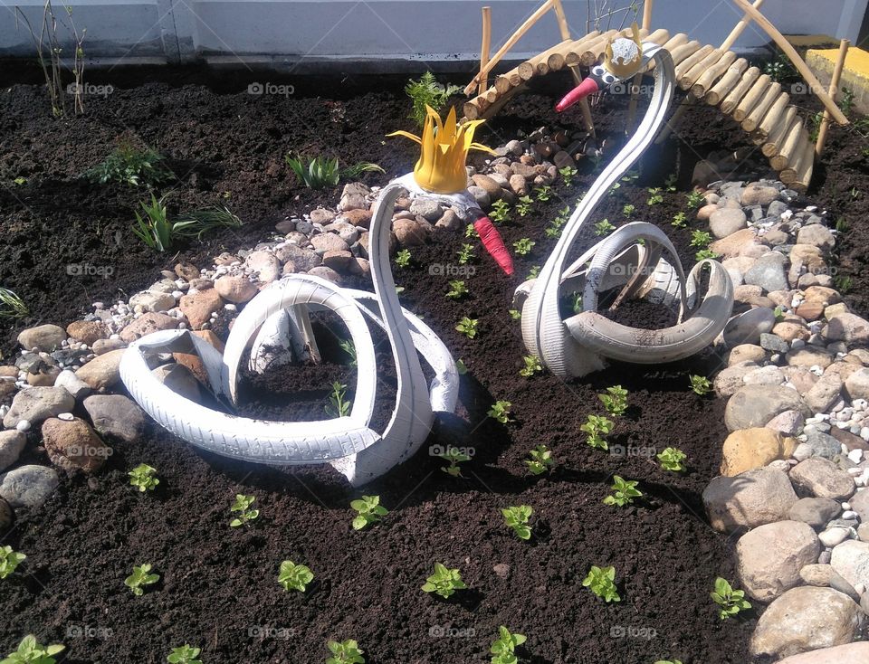 two decorative swans on a flowerbeds