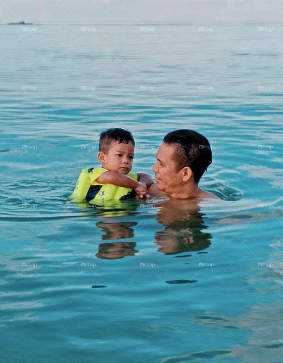 Father teach to swim at the beach