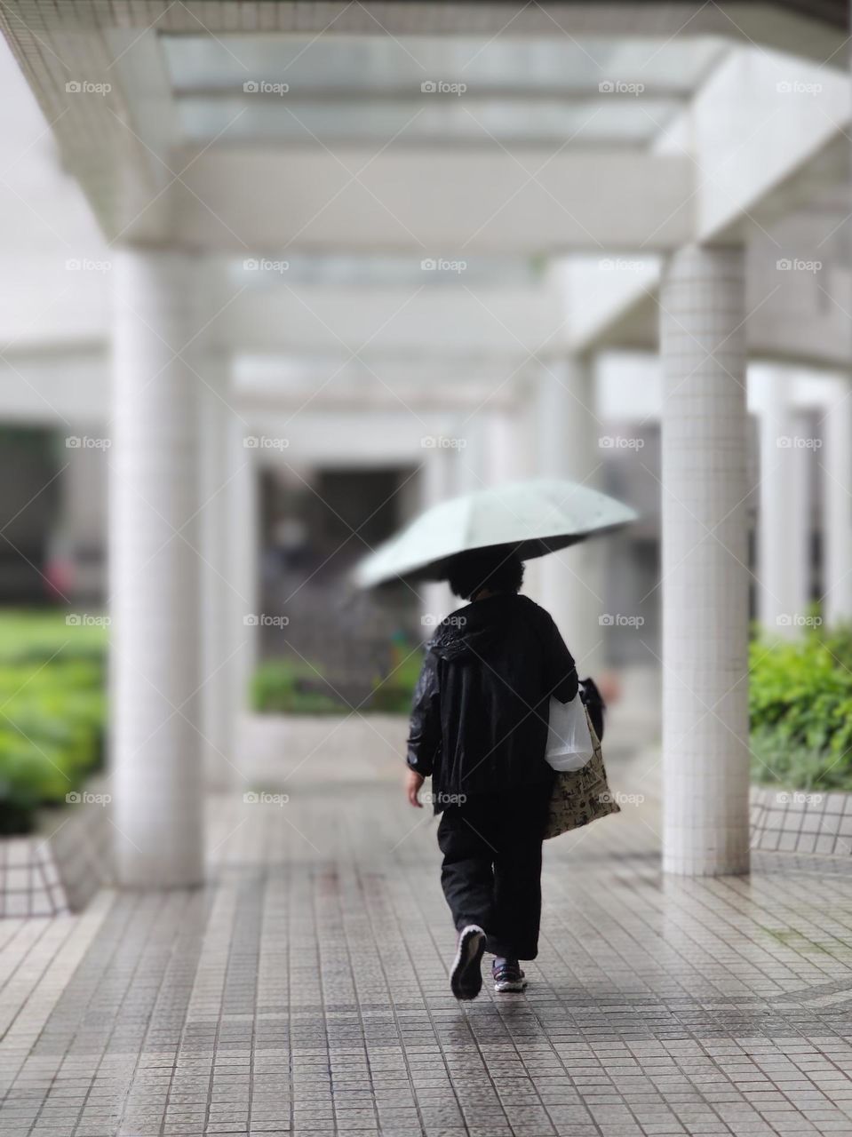 Woman walking with mint green umbrella on a rainy day