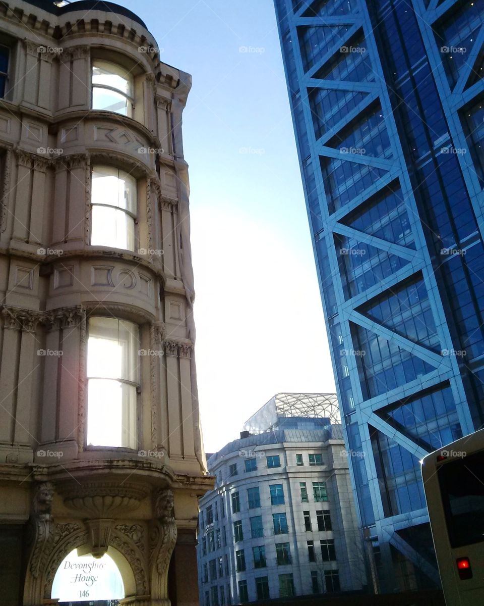 A stark contrast: a modern steel tower next to sunlight beaming through the shell of an old building in London. The old structure's been gutted, just leaving the façade for rebuilding.