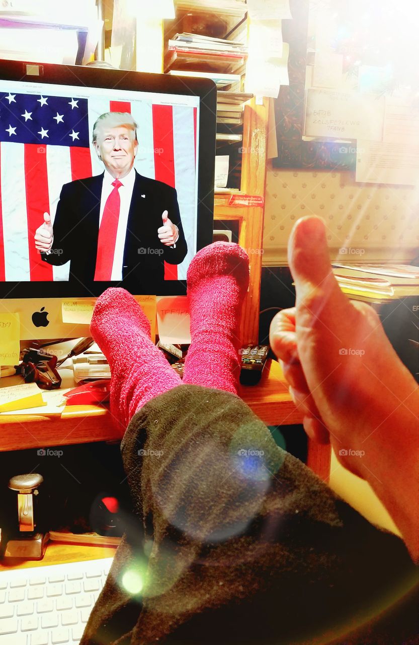 Working at computer feet up, thumbs up👍. Wallpaper is President Trump giving thumbs up👍in front of American Flag🇺🇸