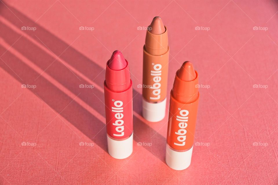 Three lipsticks on a pink background. Labello 