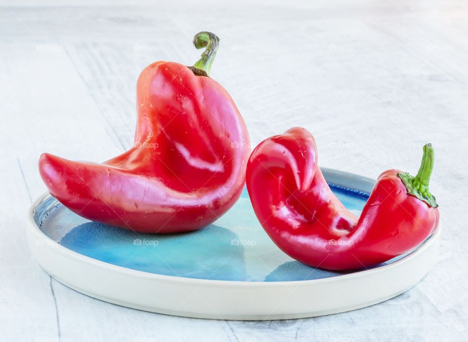 Two red ripe ugly peppers on the plate. Zero waste life concept. Trendy concept of ugly food.