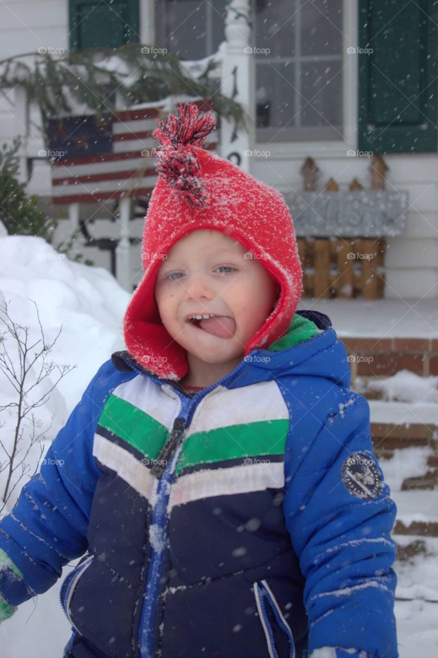 A sweet little boy tasting the snowflake that fell into his cheek. 