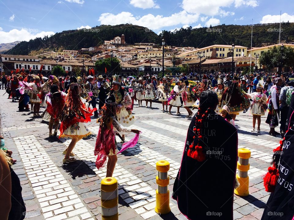 A lively parade takes off in Cuzco, with locals dressed in traditional clothing dancing through the street. 