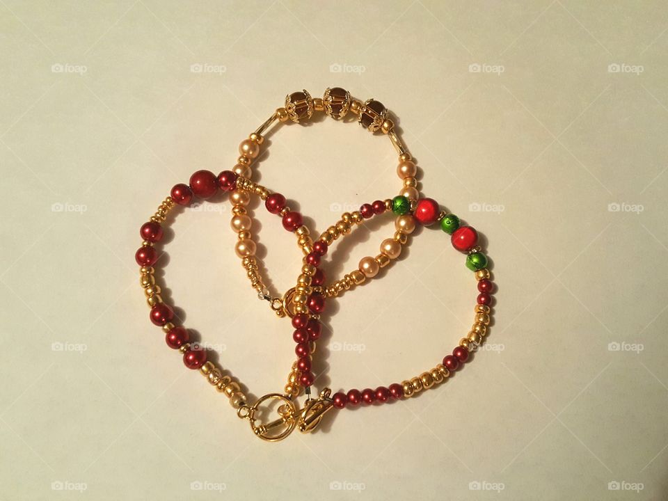 Homemade bracelets in red, gold and a bit of green.