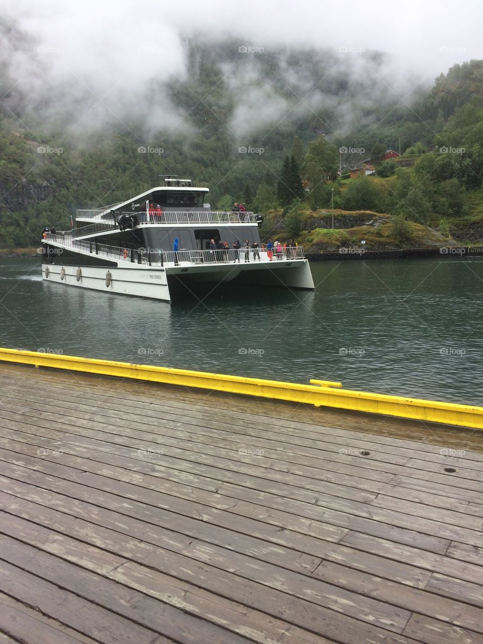 Vision of Fjords arriving Flåm after taking some tourists on a fjord sightseeing. The weather was greay and foggy, but that doesn’t stop people from traveling.