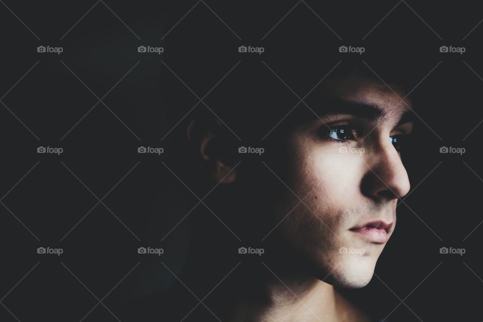 Young man in a dark room with harsh lighting