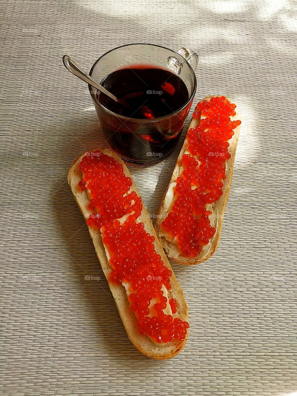 Breakfast. A cup of tea and two rolls with butter and red caviar