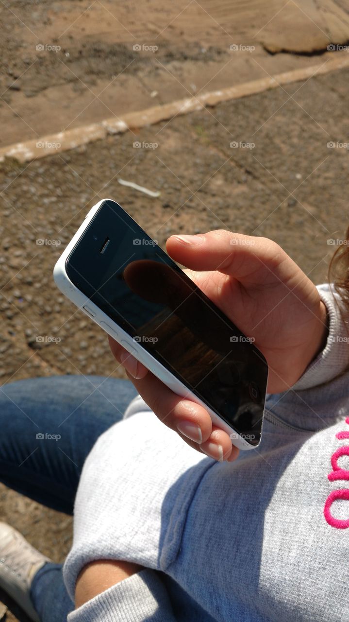 Celular na mão de menina.