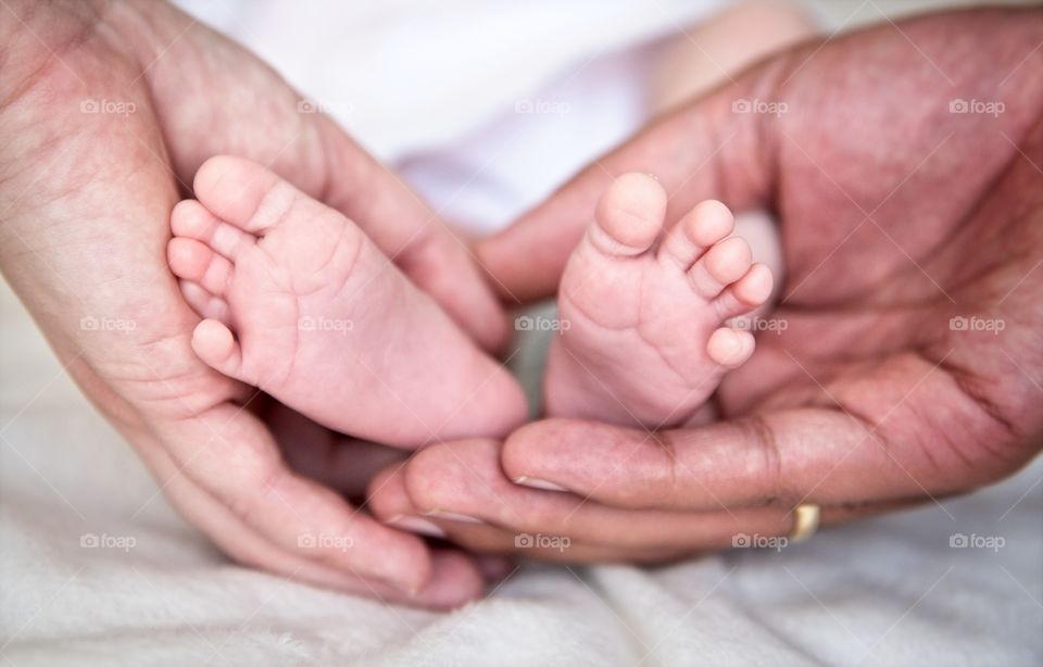 Parents hold the tiny feet of their newborn baby
