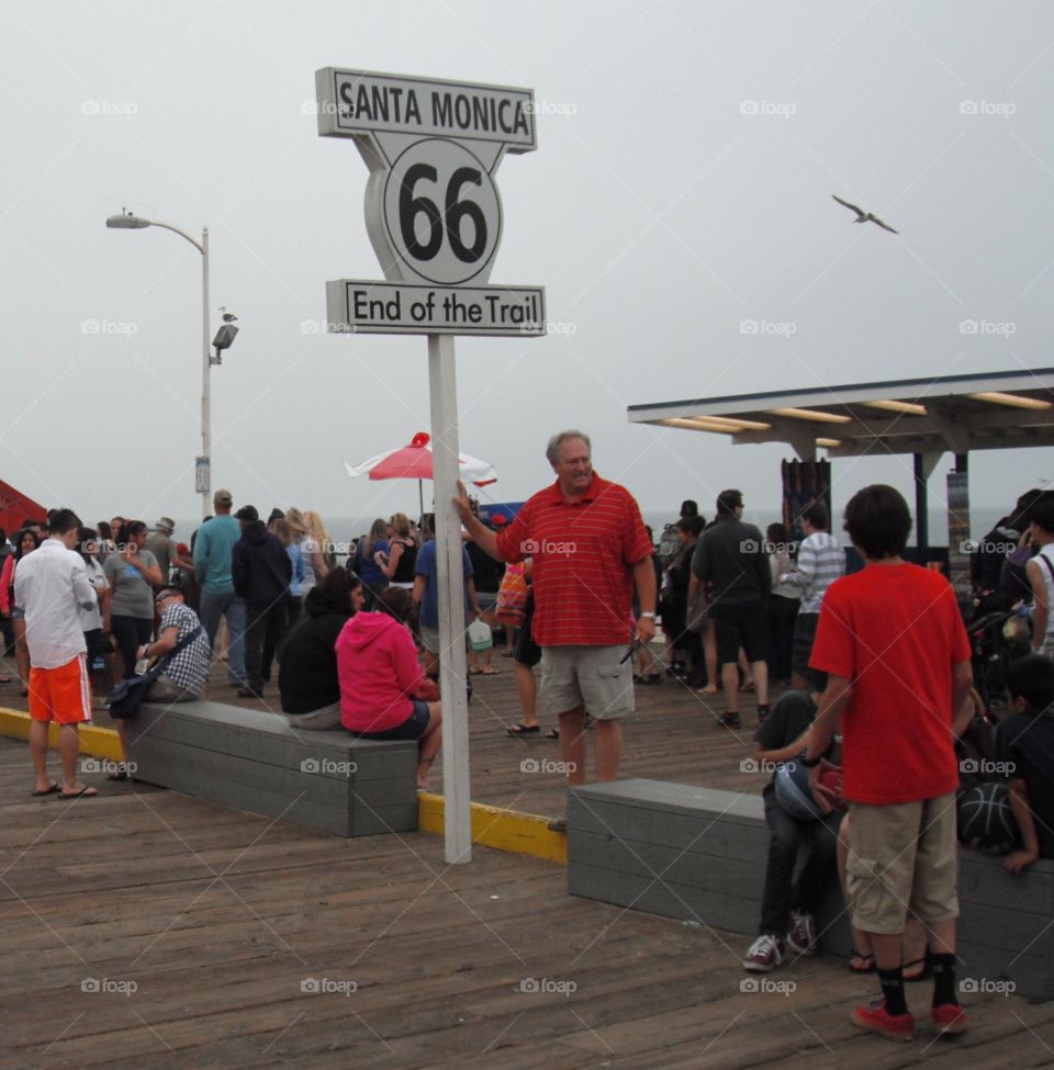 tourist standing and taking pictures to the end of route 66 in Santa Monica, Los Angeles, California