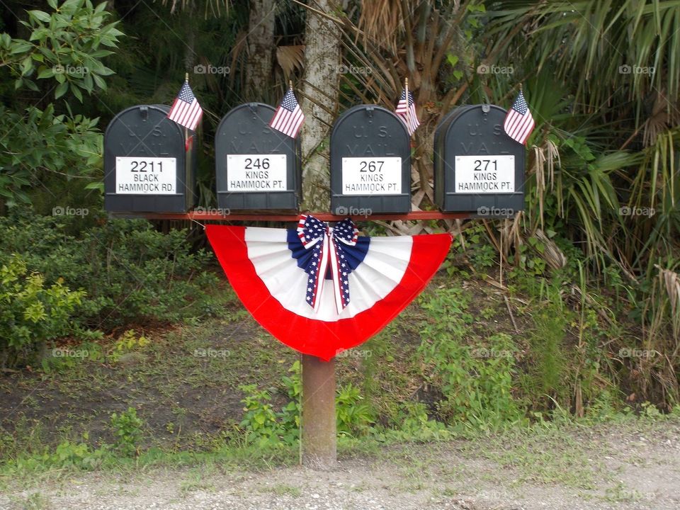 Row of mailboxes decorated with American flags and red, white and blue bunting for a patriotic holiday.