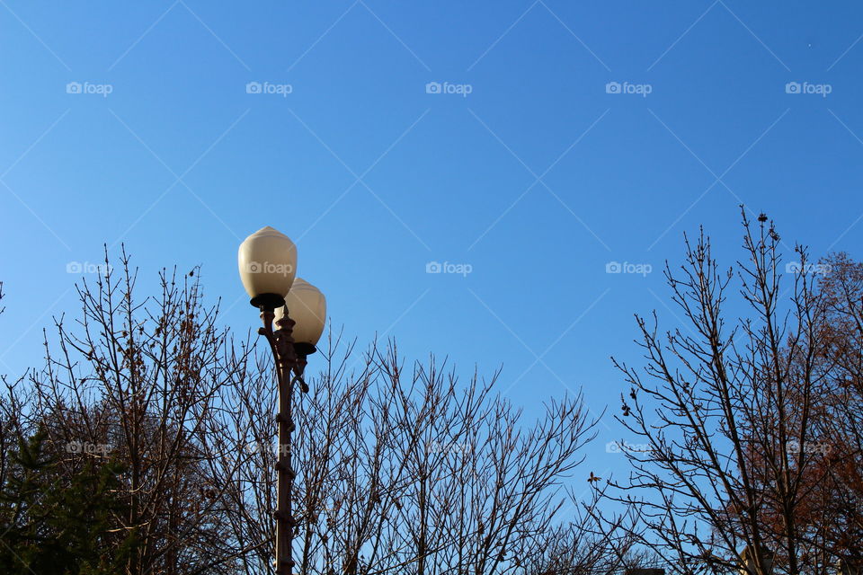 Close-up of tall lamppost and blue sky