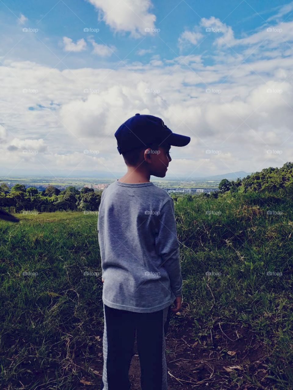 Caminando por las montañas, con vista ala ciudad. Niño observando.