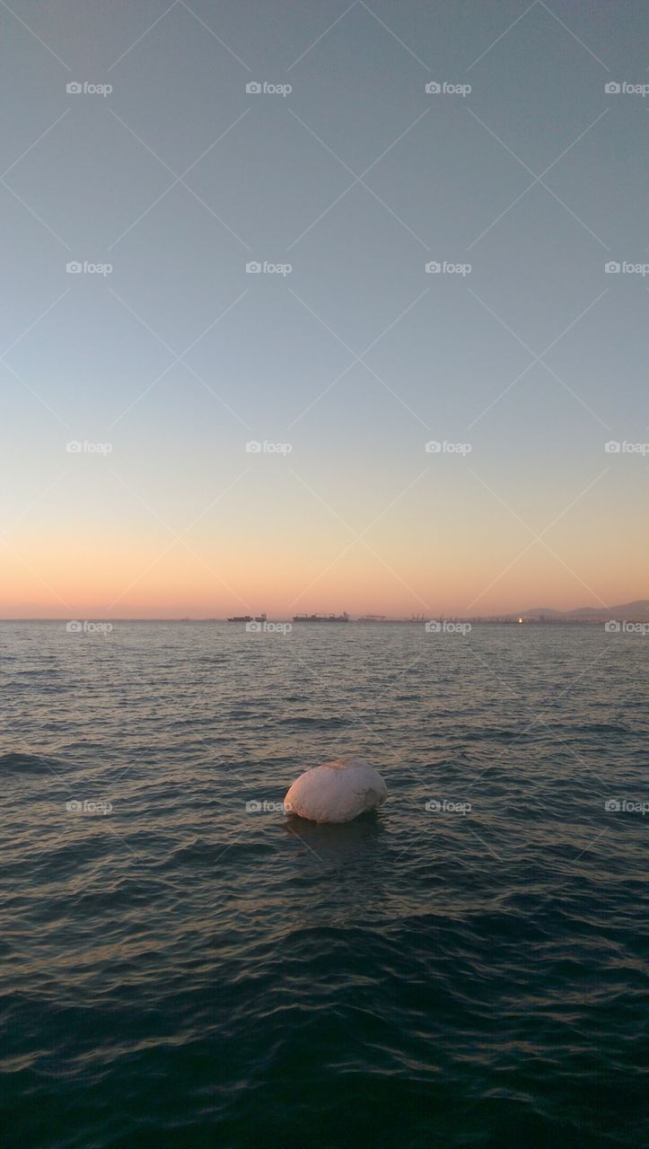 Sunset and a rock in the middle of the sea.