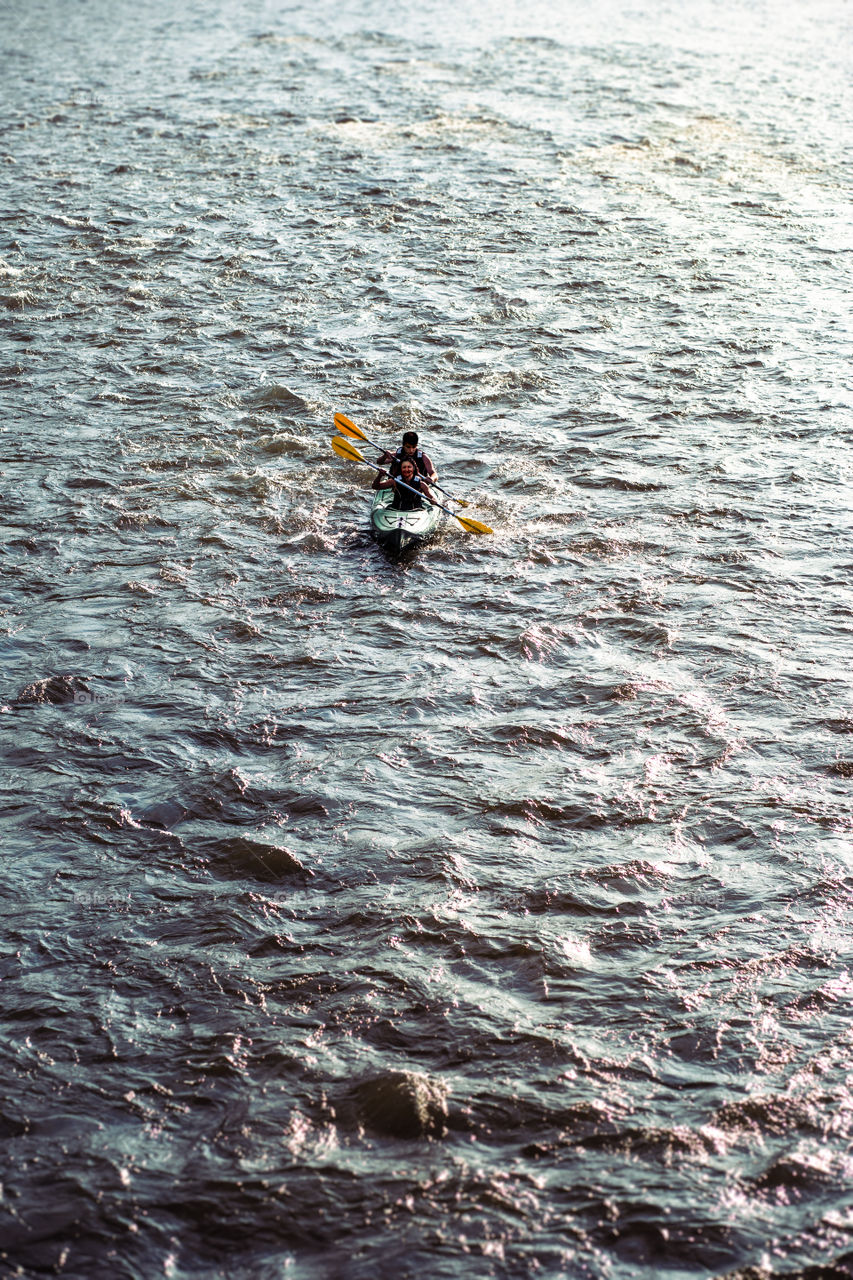 People kayaking on the Dunajec river. Two young adults sitting in a kayak and they paddling together down the river. Couple enjoying ride surrounded by small waves