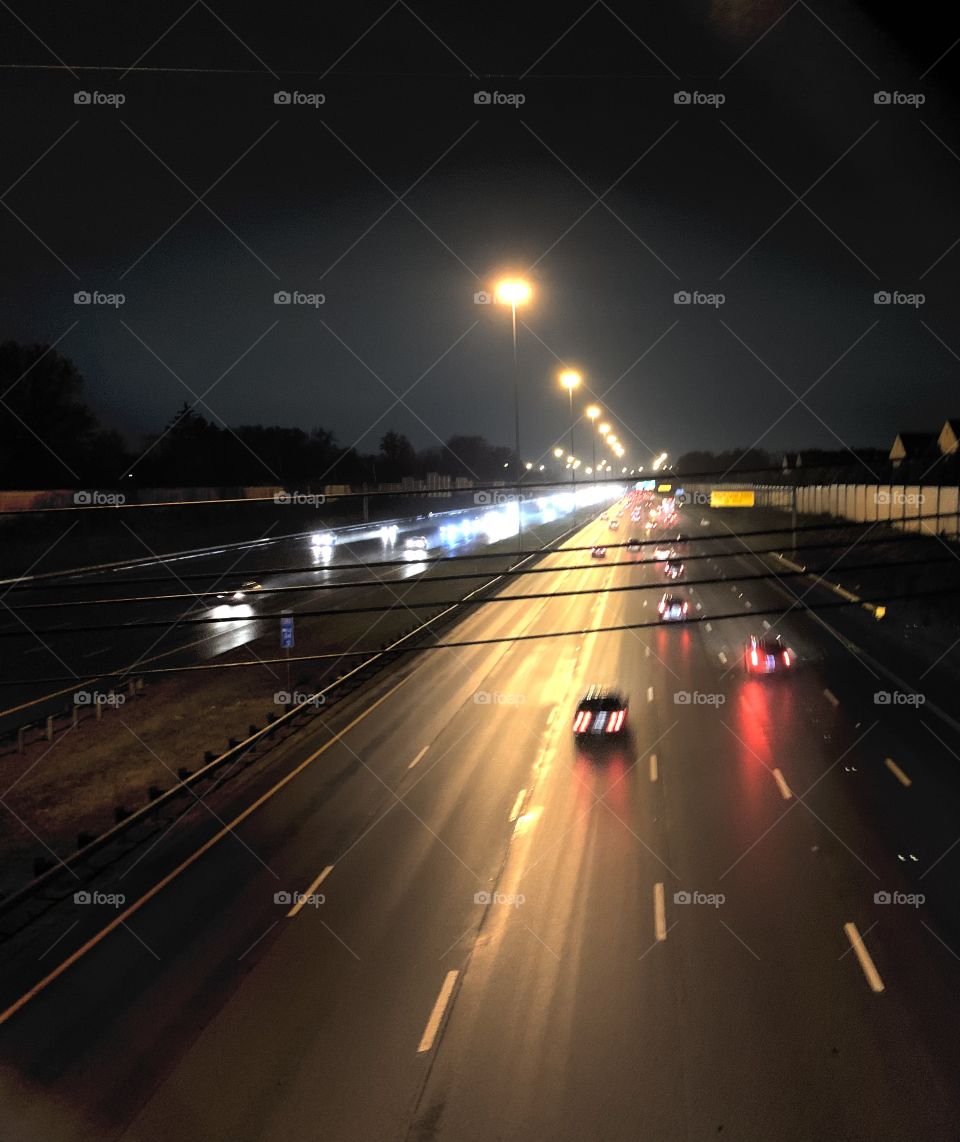 After dark, in the Midwest. A look down onto the Highway, from a city bridge. It’s raining.
