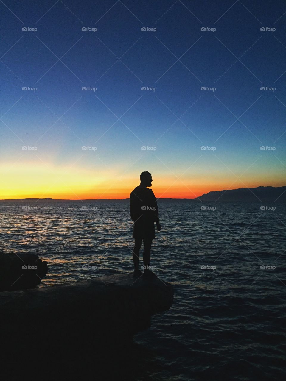 Man staring at the sea at sunset