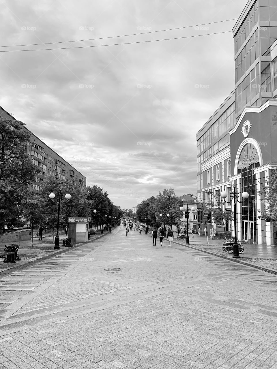 City street on a cloudy day. People are walking along the street. mood color - gray
