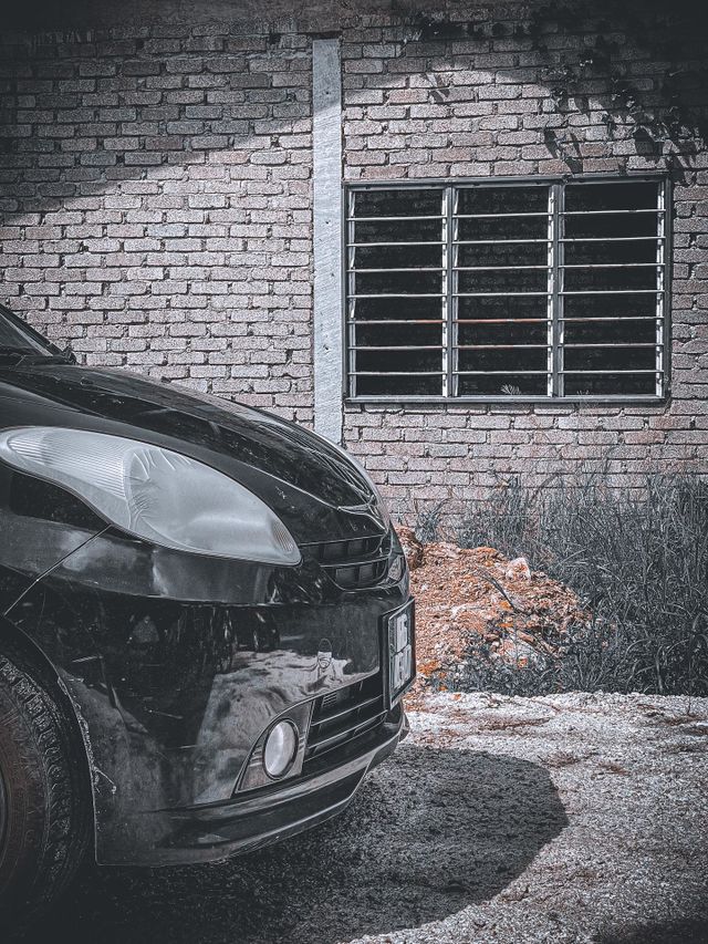 Small car black in colour with vintage surrounding and a window as a background 